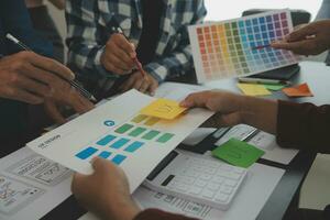 Close up ux developer and ui designer brainstorming about mobile app interface wireframe design on table with customer breif and color code at modern office.Creative digital development agency photo