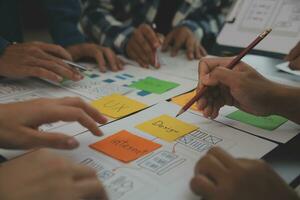 Close up ux developer and ui designer brainstorming about mobile app interface wireframe design on table with customer breif and color code at modern office.Creative digital development agency photo
