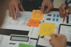 Close up ux developer and ui designer brainstorming about mobile app interface wireframe design on table with customer breif and color code at modern office.Creative digital development agency photo