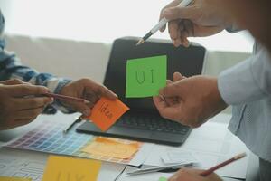 Close up ux developer and ui designer brainstorming about mobile app interface wireframe design on table with customer breif and color code at modern office.Creative digital development agency photo