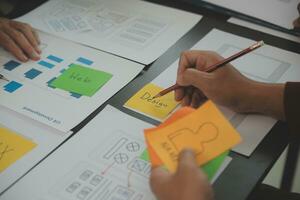 Close up ux developer and ui designer brainstorming about mobile app interface wireframe design on table with customer breif and color code at modern office.Creative digital development agency photo