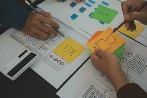 Close up ux developer and ui designer brainstorming about mobile app interface wireframe design on table with customer breif and color code at modern office.Creative digital development agency photo