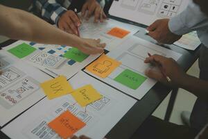 Close up ux developer and ui designer brainstorming about mobile app interface wireframe design on table with customer breif and color code at modern office.Creative digital development agency photo