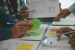 Close up ux developer and ui designer brainstorming about mobile app interface wireframe design on table with customer breif and color code at modern office.Creative digital development agency photo