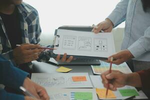 Close up ux developer and ui designer brainstorming about mobile app interface wireframe design on table with customer breif and color code at modern office.Creative digital development agency photo