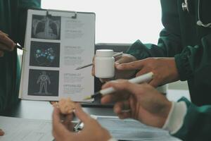 Multiracial team of doctors discussing a patient standing grouped in the foyer looking at a tablet computer, close up view photo