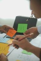 Close up ux developer and ui designer brainstorming about mobile app interface wireframe design on table with customer breif and color code at modern office.Creative digital development agency photo