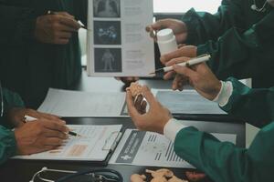 Multiracial team of doctors discussing a patient standing grouped in the foyer looking at a tablet computer, close up view photo