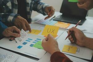 Close up ux developer and ui designer brainstorming about mobile app interface wireframe design on table with customer breif and color code at modern office.Creative digital development agency photo