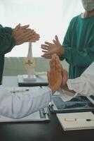 Mature doctors and young nurses stacking hands together at hospital. Close up hands of medical team stacking hands. Group of successful medical doctors and nurses stack of hands. photo