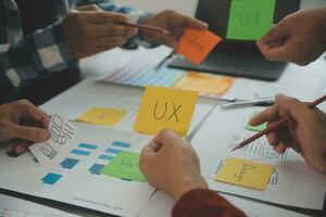 Close up ux developer and ui designer brainstorming about mobile app interface wireframe design on table with customer breif and color code at modern office.Creative digital development agency photo