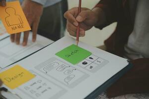 Close up ux developer and ui designer brainstorming about mobile app interface wireframe design on table with customer breif and color code at modern office.Creative digital development agency photo