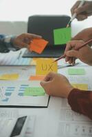 Close up ux developer and ui designer brainstorming about mobile app interface wireframe design on table with customer breif and color code at modern office.Creative digital development agency photo