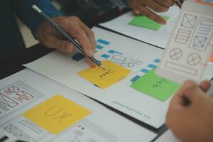 Close up ux developer and ui designer brainstorming about mobile app interface wireframe design on table with customer breif and color code at modern office.Creative digital development agency photo