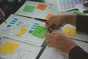 Close up ux developer and ui designer brainstorming about mobile app interface wireframe design on table with customer breif and color code at modern office.Creative digital development agency photo