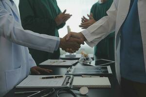 Mature doctors and young nurses stacking hands together at hospital. Close up hands of medical team stacking hands. Group of successful medical doctors and nurses stack of hands. photo