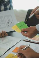 Close up ux developer and ui designer brainstorming about mobile app interface wireframe design on table with customer breif and color code at modern office.Creative digital development agency photo