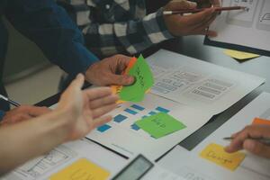 Close up ux developer and ui designer brainstorming about mobile app interface wireframe design on table with customer breif and color code at modern office.Creative digital development agency photo