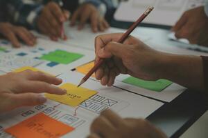 Close up ux developer and ui designer brainstorming about mobile app interface wireframe design on table with customer breif and color code at modern office.Creative digital development agency photo