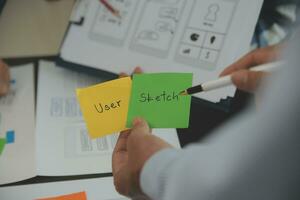 Close up ux developer and ui designer brainstorming about mobile app interface wireframe design on table with customer breif and color code at modern office.Creative digital development agency photo