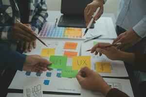 Close up ux developer and ui designer brainstorming about mobile app interface wireframe design on table with customer breif and color code at modern office.Creative digital development agency photo