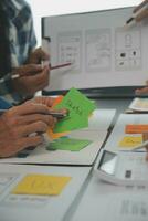 Close up ux developer and ui designer brainstorming about mobile app interface wireframe design on table with customer breif and color code at modern office.Creative digital development agency photo