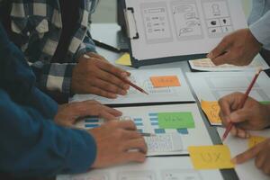 Close up ux developer and ui designer brainstorming about mobile app interface wireframe design on table with customer breif and color code at modern office.Creative digital development agency photo