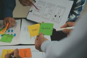 Close up ux developer and ui designer brainstorming about mobile app interface wireframe design on table with customer breif and color code at modern office.Creative digital development agency photo