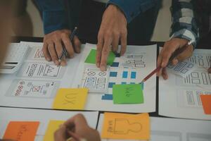 Close up ux developer and ui designer brainstorming about mobile app interface wireframe design on table with customer breif and color code at modern office.Creative digital development agency photo