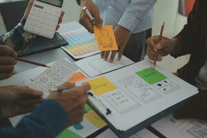 Close up ux developer and ui designer brainstorming about mobile app interface wireframe design on table with customer breif and color code at modern office.Creative digital development agency photo