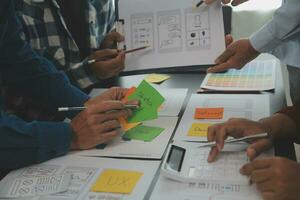 Close up ux developer and ui designer brainstorming about mobile app interface wireframe design on table with customer breif and color code at modern office.Creative digital development agency photo