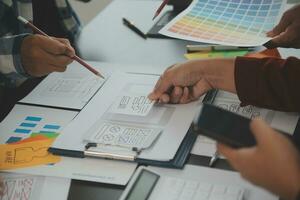 Close up ux developer and ui designer brainstorming about mobile app interface wireframe design on table with customer breif and color code at modern office.Creative digital development agency photo