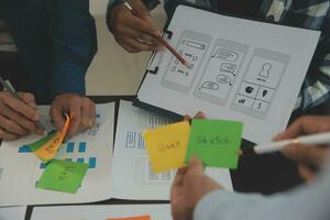 Close up ux developer and ui designer brainstorming about mobile app interface wireframe design on table with customer breif and color code at modern office.Creative digital development agency photo