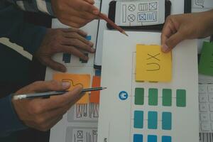 Close up ux developer and ui designer brainstorming about mobile app interface wireframe design on table with customer breif and color code at modern office.Creative digital development agency photo