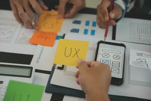 Close up ux developer and ui designer brainstorming about mobile app interface wireframe design on table with customer breif and color code at modern office.Creative digital development agency photo