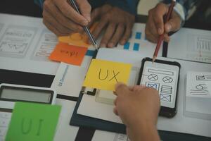 Close up ux developer and ui designer brainstorming about mobile app interface wireframe design on table with customer breif and color code at modern office.Creative digital development agency photo