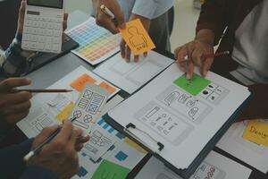 Close up ux developer and ui designer brainstorming about mobile app interface wireframe design on table with customer breif and color code at modern office.Creative digital development agency photo