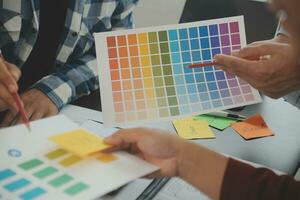 Close up ux developer and ui designer brainstorming about mobile app interface wireframe design on table with customer breif and color code at modern office.Creative digital development agency photo