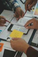 Close up ux developer and ui designer brainstorming about mobile app interface wireframe design on table with customer breif and color code at modern office.Creative digital development agency photo