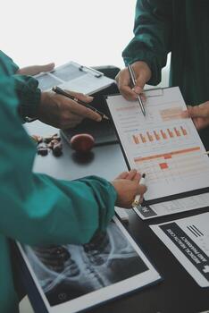 Multiracial team of doctors discussing a patient standing grouped in the foyer looking at a tablet computer, close up view photo