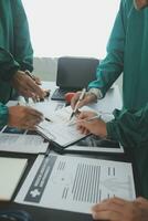 multirracial equipo de doctores que se discute un paciente en pie agrupado en el vestíbulo mirando a un tableta computadora, cerca arriba ver foto