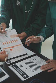 Multiracial team of doctors discussing a patient standing grouped in the foyer looking at a tablet computer, close up view photo