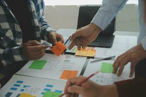 Close up ux developer and ui designer brainstorming about mobile app interface wireframe design on table with customer breif and color code at modern office.Creative digital development agency photo