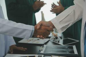 Mature doctors and young nurses stacking hands together at hospital. Close up hands of medical team stacking hands. Group of successful medical doctors and nurses stack of hands. photo