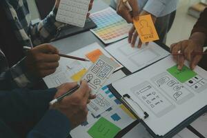 Close up ux developer and ui designer brainstorming about mobile app interface wireframe design on table with customer breif and color code at modern office.Creative digital development agency photo