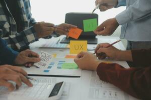 Close up ux developer and ui designer brainstorming about mobile app interface wireframe design on table with customer breif and color code at modern office.Creative digital development agency photo