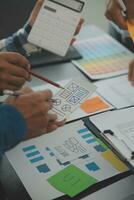 Close up ux developer and ui designer brainstorming about mobile app interface wireframe design on table with customer breif and color code at modern office.Creative digital development agency photo