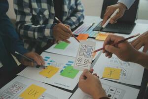 Close up ux developer and ui designer brainstorming about mobile app interface wireframe design on table with customer breif and color code at modern office.Creative digital development agency photo