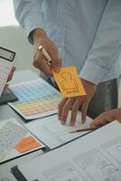 Close up ux developer and ui designer brainstorming about mobile app interface wireframe design on table with customer breif and color code at modern office.Creative digital development agency photo