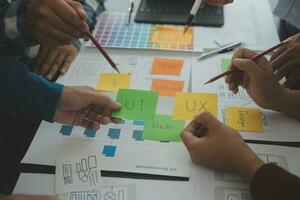 Close up ux developer and ui designer brainstorming about mobile app interface wireframe design on table with customer breif and color code at modern office.Creative digital development agency photo